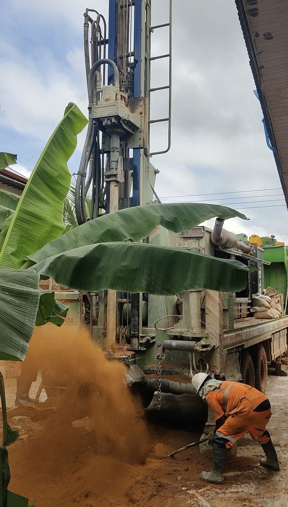An Apex rig drilling, cuttings blowing clear of the hole as a crew member works alongside