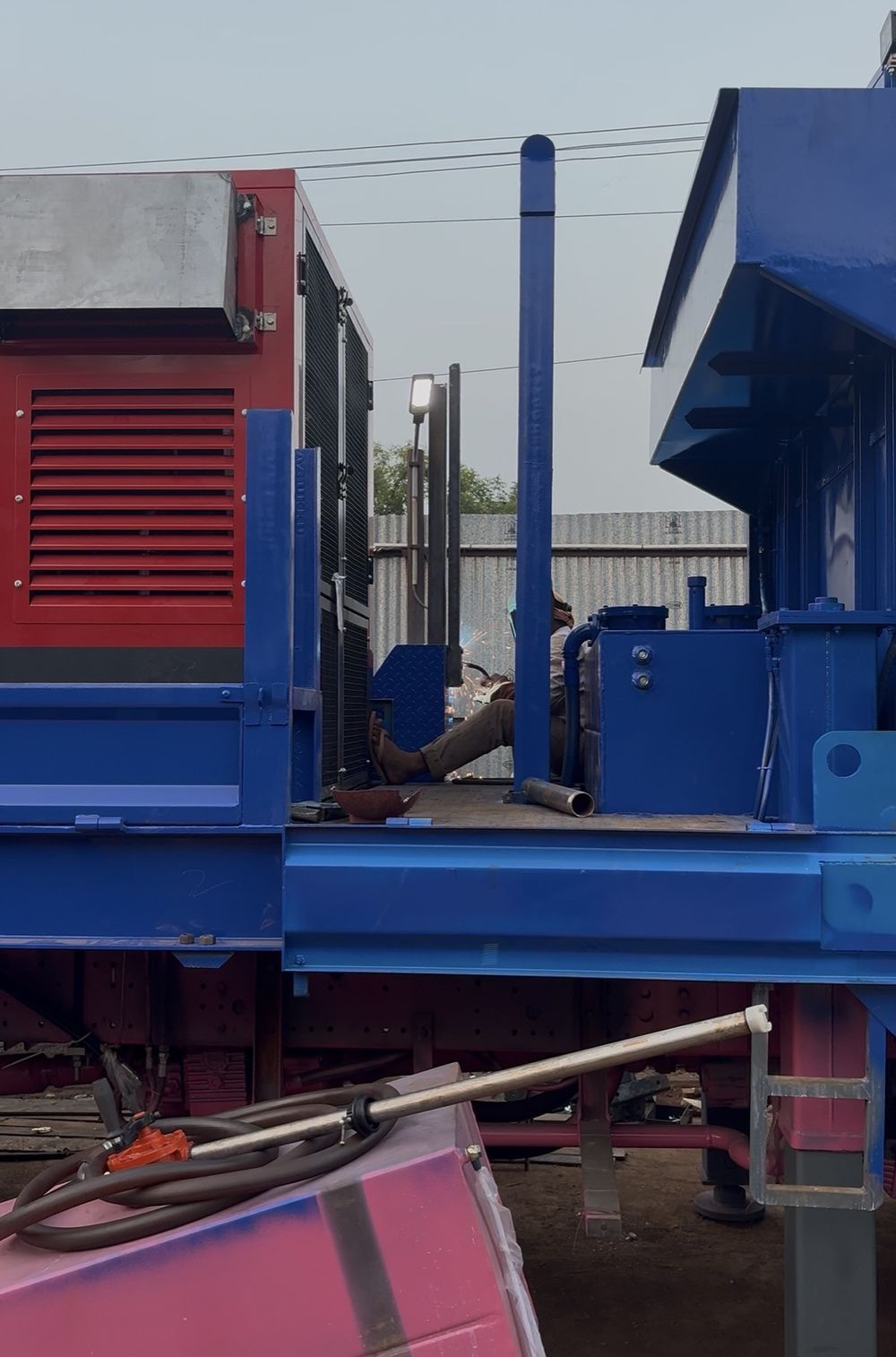 Rig sections in the Apex fabrication yard in India, freshly painted, with a fitter working behind